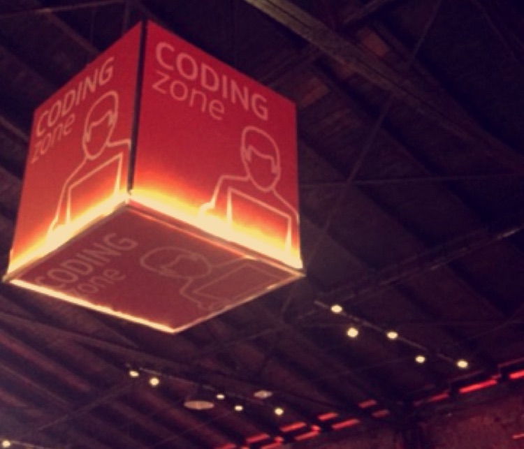 Ein hängendes „Coding zone“-Schild über einer Hackathon-Fläche